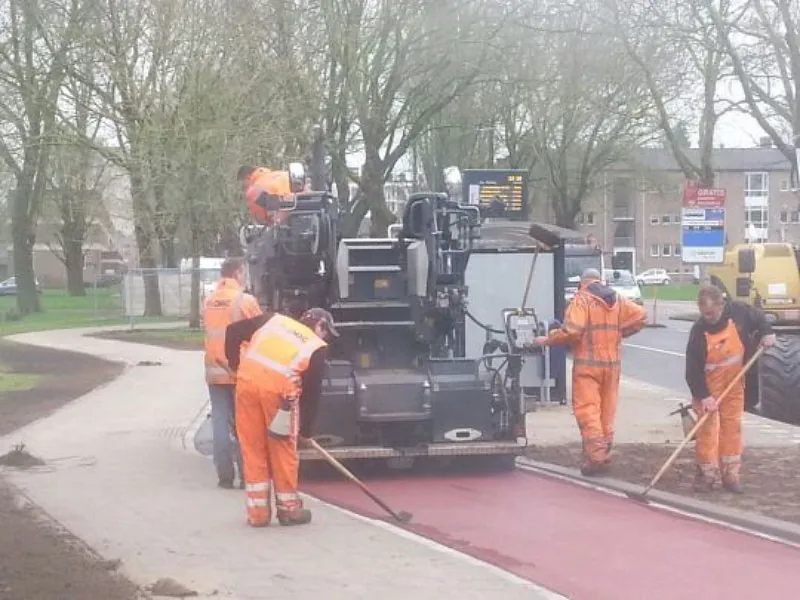 Gemeentewerkers die een fietspad netjes afwerken.